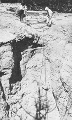 Grand Canyon Caverns winch in 1938 black and white photo of a winch, men, and a sinkhole with a rope descending into it