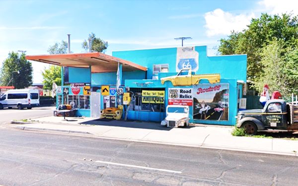 former gas station, painted turqouise with Route 66 signage, old cars, and a flat orange canopy