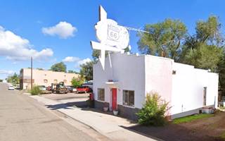 Green Door Bar, Ash Fork AZ bar with whitewashed neon sign, building painted white, Route 66 passing in front of it