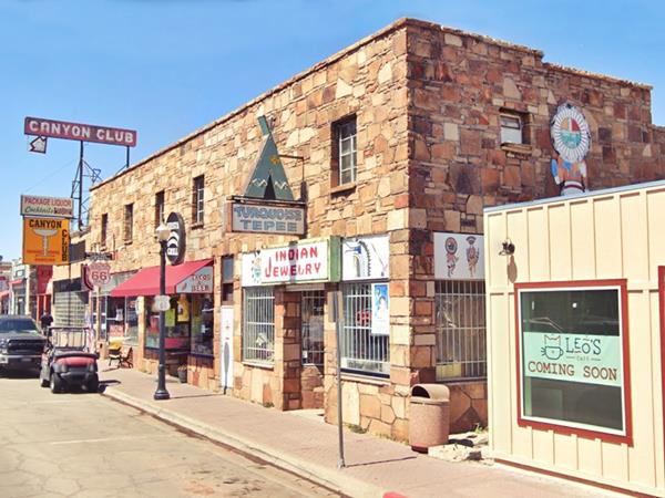 irreglular flagstone building, two stories cars, stores in the building