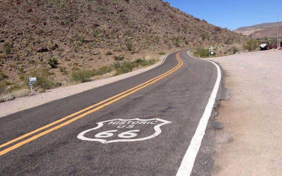 US 66 shield painted on winding highway surface in the mountains