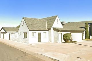 cottage style building, steep cross gable roof, painted gray