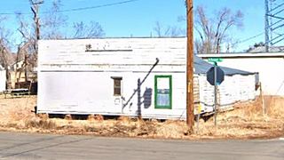 Cottage hotel in 2021, Seligman AZ woodframe building, peeling white paint, overgrown yard