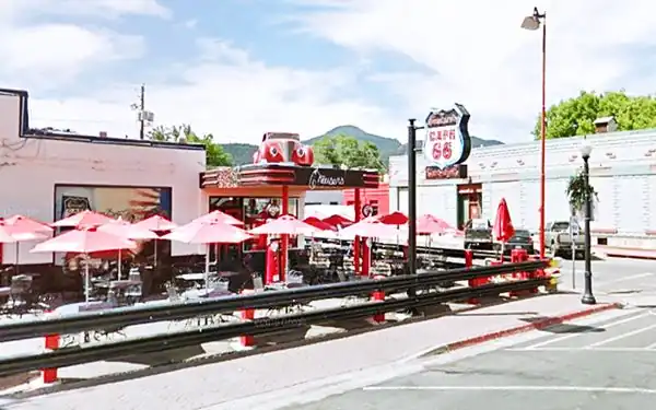 corner cafe bar, former gas station, flat canopy with car on it, gas pumps, parasols, neon sign