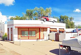 DeSoto barber shop in 2022, Ash Fork AZ former gas station, with a car on the roof, US 66 on the left