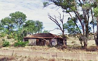 old gas station, Sanders AZ vacant builiding hipped roof under some trees with US 66 running in front