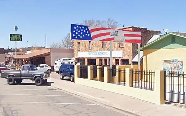 long sign with an eagle head & American flag painted on by yellow gable roof bldg