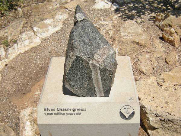 a piece of dark rock on a concrete pedestal identified as Elves Chasm Gneis and age given as 1,840 million years