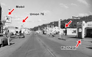 black and white 1940s, street intersections, four gas stations, cars, people