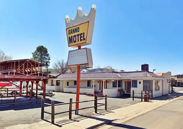 former motel, yellow neon sign, words GRAND MOTEL in black letters. Building behind
