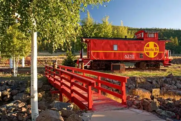 red caboose used as a room in this motel, trees, forested hill, and pedestrian bridge