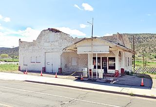 old white cement block gas station, pumps, canopy and orange cones marking it for safety reasons facing Route 66