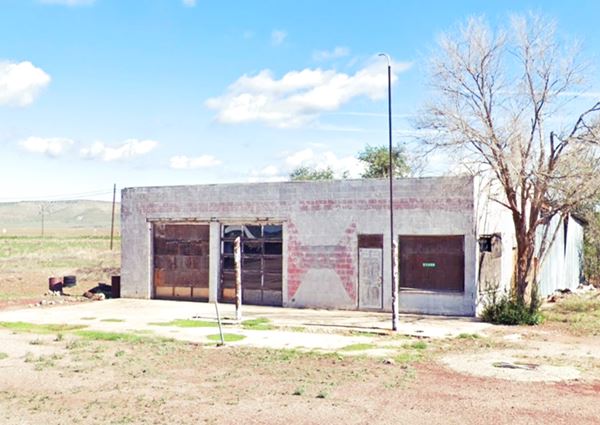 icebox shaped gas station, two multipanel glass service bays, corner office, empty pumps island