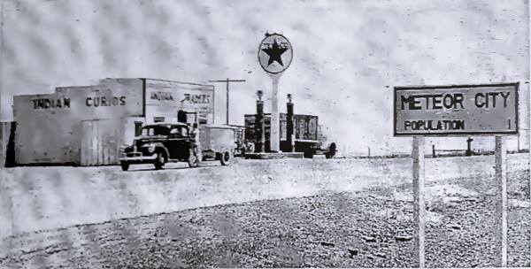 black and white photo from 1942 of a trading post, cars, Texaco sign and US66, the sign reads METEOR CITY POPULATION 1