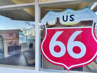 Postcard motel in 2022, Seligman AZ Route 66 shield logo of a motel painted on a window, reflecting other buildings