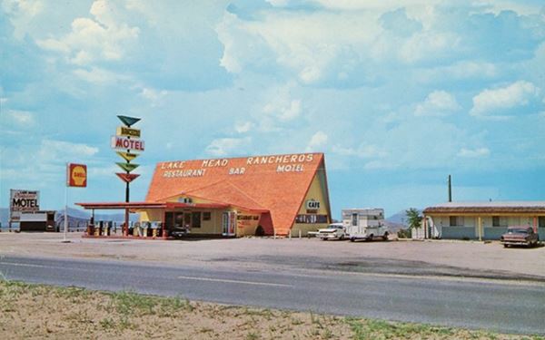 shell gas station with steep faded red gable roof building, cars and motel to the right