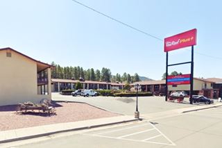 modern motel, forested hill behind 2 story gable roof bldg, red sign