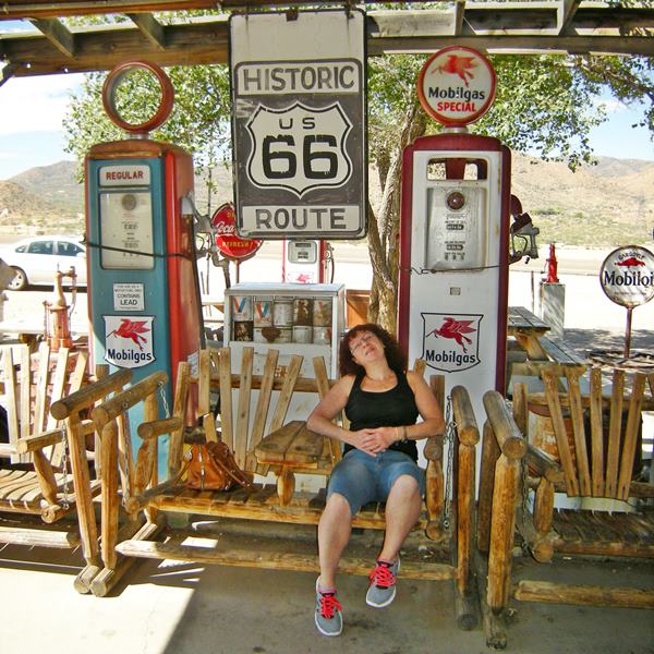 slouching on a wood bench by the vintage signs and gas pumps