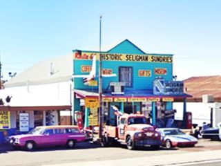 Ted Sundries Seligman, Route 66 bright blue facade, vintage cars, flagpole and gable roof store