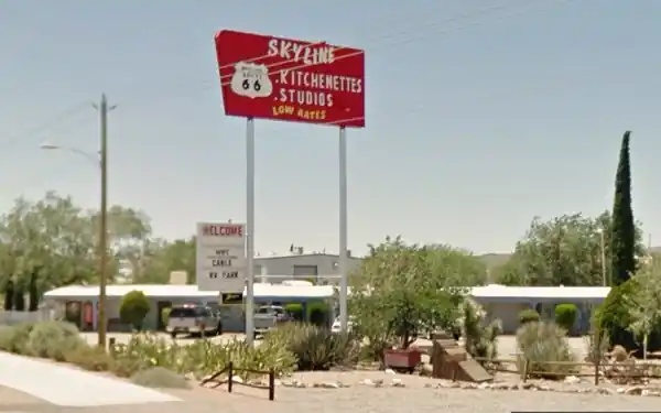 Skyline Motel today neon sign, dirt parking area, shrubs and apartments