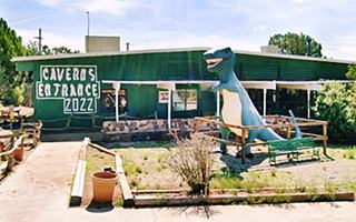 T-rex statue by gable roof building