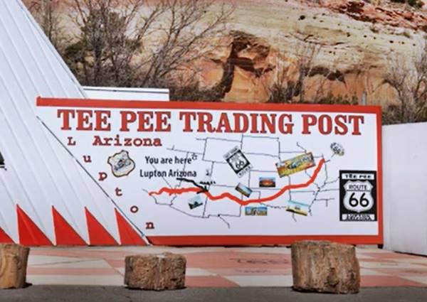 large map of Route 66 painted on a white wall, tepee wall on the left, cliff behin