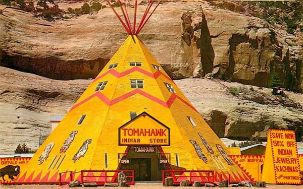 large yellow tepee with windows in it and yellow signs. Red cliffs behind