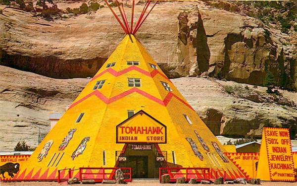 Tepee at Tomahawk Indian Store Lupton large yellow tepee with windows in it and yellow signs. Red cliffs behind