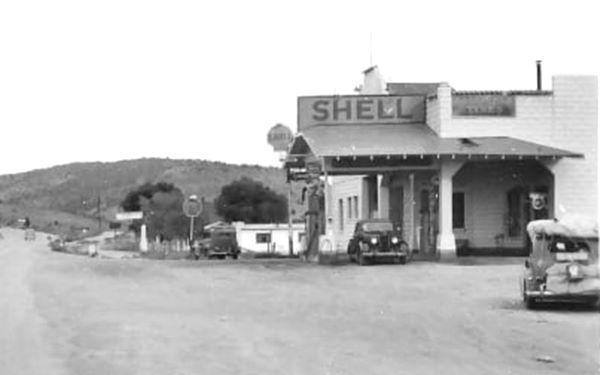 detail from a 1930s black and white postcard, cars, US66 and on the right a Shell cas station