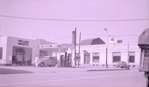 black and white 1940s photo Mobil station, flat canopy, gas pumps, attendant and cars