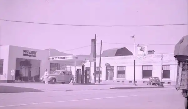 black & white 1940s photo Mobil station, flat canopy, gas pumps, attendant and cars