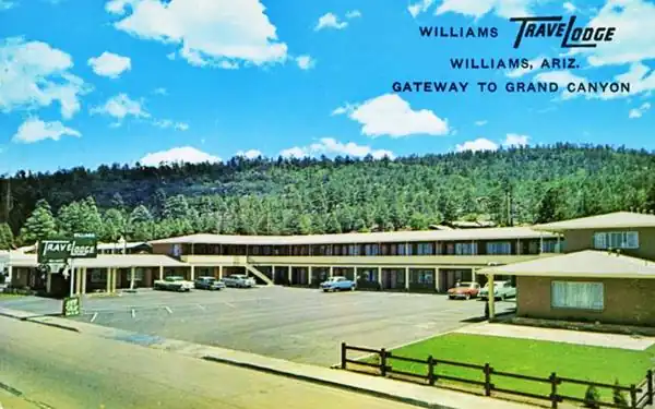 2-story gable roof U-shaped motel, 1960s postcard, pine trees on hill behind