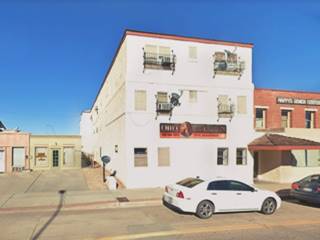 3 story block shaped hotel from 1926, white stucco, facing Route 66