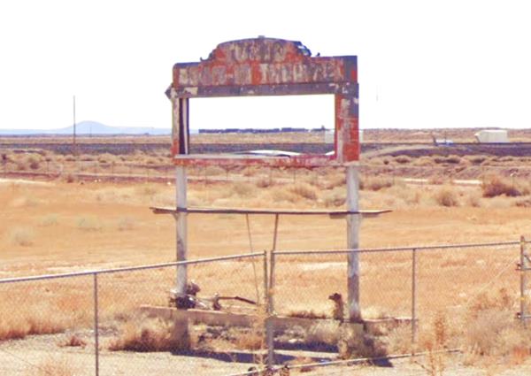 rusty faded drive in theater marquee next to Route 66 in an arid field