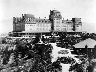 1890s, first Raymond Hotel South Pasadena black and white 1890s photo, building with central tower and corner towers, French styled roof, four stories, mountains beyond, garden around it