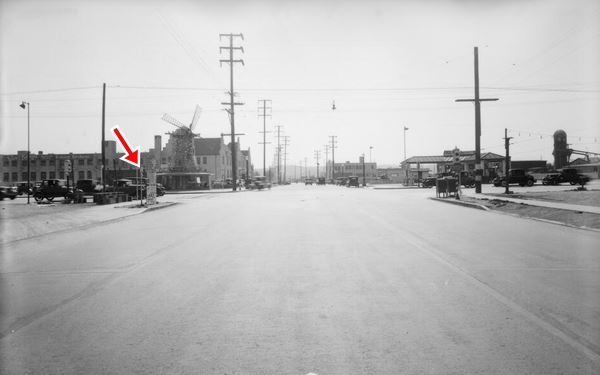 Intersection of Fletcher Drive and North San Fernando Road, 1932 Los Angeles CA black and white photo, 1932 cars on a crossroads, to the upper left is a windmill on top of a bakery, to the upper right a gas station. Traffic lights