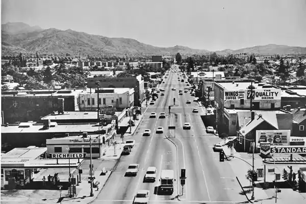 Foothill Boulevard looking east, Azusa, 1965 black and white 1965 air view looking east along Foothill with cars, buildings, gas stations, signs, mountains in the distance
