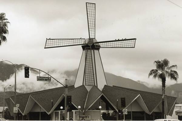 black and white picture of an 16 sided building with a steeple with a windmill on it
