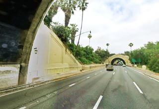 Figueroa Street Tunnels, Los Angeles, 1938 black and white, cars driving along a 2 way street in hilly area, with several tunnels and open stretches between them. 1938
