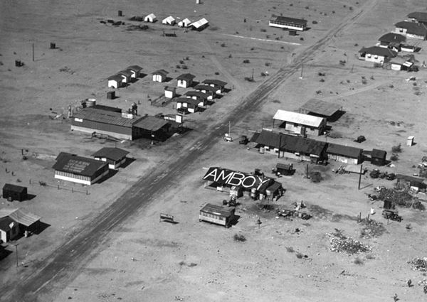 black and white aerial view of Amboy CA 1925: scattered buildings, cabins, gas stations and highway running lower left to upper right