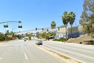 Pacific Electric (PE) trail bridge over Route 66 in Cucamonga bridge spans 4 lane hwy, decorated with cars in relief, palm trees left