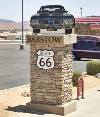 stone column topped by a panel that looks like a car seen head on, Route 66 shield on column, car license plate reads ROUTE 66