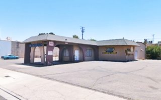 former gas station, tiled canopy and office on a corner, now a cleaners