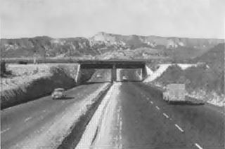 AT&SF viaduct 1950s US 66, Cajon Pass Black and white 1950s, 4-lane US66 passes under a Railway viaduct, arid scenery, hills, vehicles