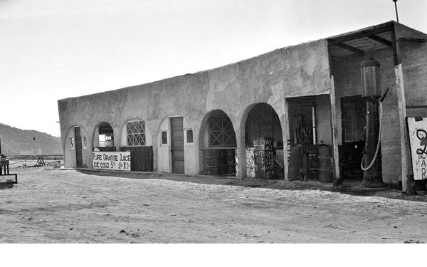 1920s Alray gas station on US66 in Cajon Pass black and white 1920s, shabby adobe style building with arches, and gas pump, desertic setting