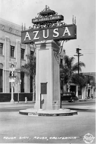 1939 view Azusa Monument and sign on Foothill, Azusa, California black and white 1939 by Burton Frasher, sign reads AZUSA topped by smaller sign reading SAN GABRIEL CANYON and an arrow mounted on top of a box-like masonry pillar in the middle of Foothill Blvd