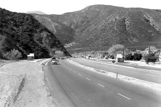 Blue Cut 1950s US66 black and white steep hills and Route 66 running as 4-lane highway between them, cars, c.1950s