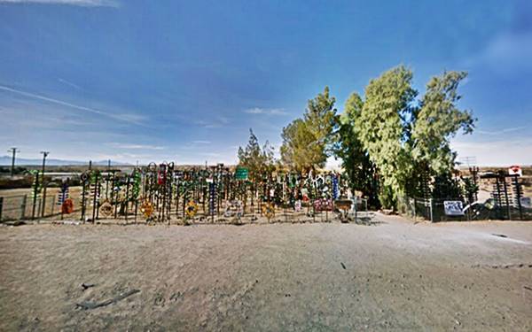 Bottle Tree Ranch in 2018 US 66 artwork with bottles and steel poles by the highway, gravel shoulder and parking area
