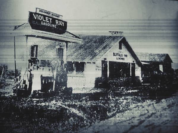 black and white, 1929 gable roof BUFFALO INN to the right, gas pumps under VIOLET RAY sign