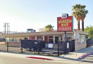 diner glassed in, on a corner enclosed with a steel fence, 2 palm trees, US66 to the right